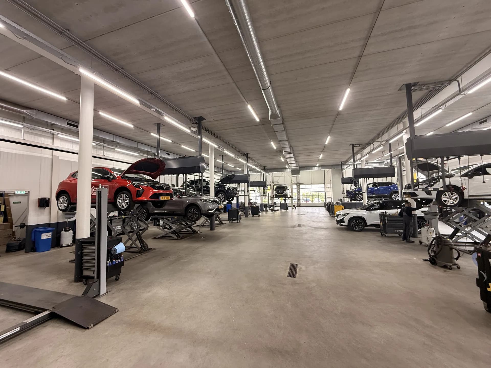 Werkplaats met LED-lijnarmaturen boven de hefbruggen bij Hedin Automotive Tilburg